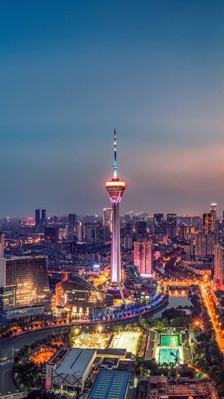 Torre de la Perla del Oeste iluminada por la noche, destacando como un hito moderno en el horizonte de la ciudad.